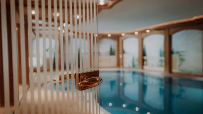 Geöffnete Glastür mit goldenem Griff zum Hallenbad