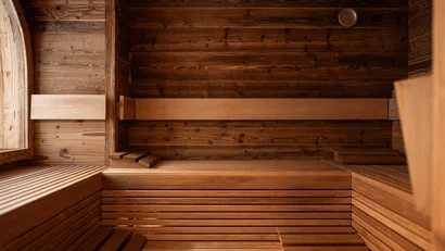Innenansicht einer leeren Holzsauna mit Bänken und Kopfstützen