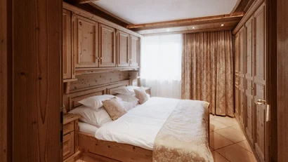 Cozy bedroom with wooden furniture and large window with curtains