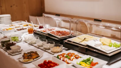 Appetizer buffet with cold cuts, cheese, vegetables, and sauces in a buffet line