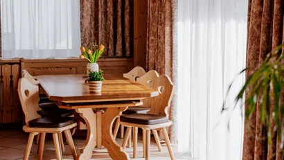 Cozy dining area with wooden table, chairs, and curtains by large windows