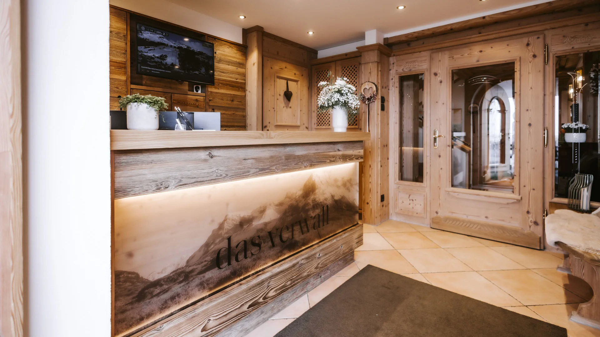 Reception desk with wooden paneling and TV in warm hotel interior