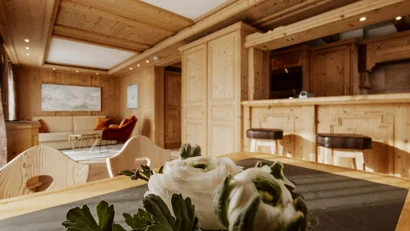 Cozy living space with wooden ceiling and flowers on the table in foreground