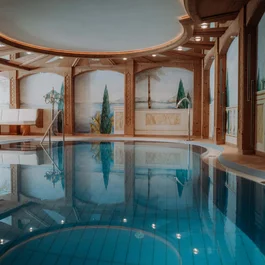 Innenpool mit bemalten Wänden und Holzbalken im Wellnessbereich