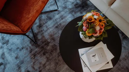 Blumenstrauß auf rundem schwarzem Tisch mit Büchern und Teppich darunter