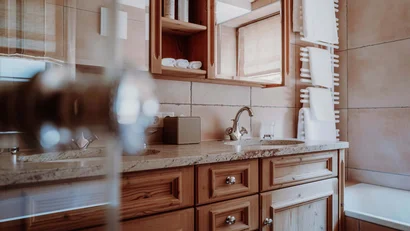 Badezimmer mit Holzwaschbeckenunterschrank und Handtuchwärmer an beige Fliesenwand