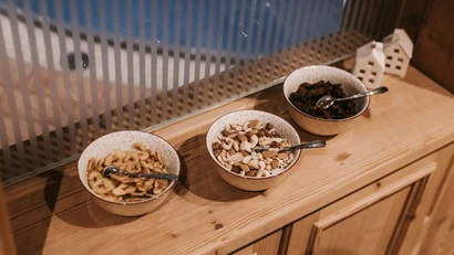 Bowls with nuts and dried fruits on wooden table near window