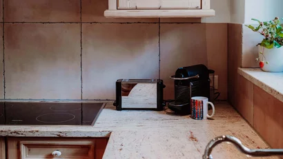 Küche mit Holzmöbeln, Herd, Kaffeemaschine und Spüle