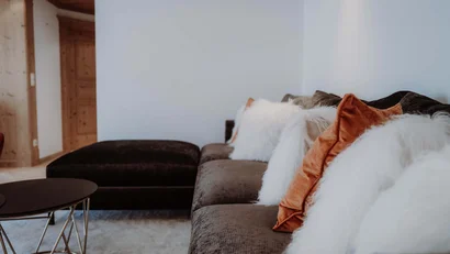 Braunes Sofa mit weißen und orangefarbenen Kissen in modernem Wohnzimmer