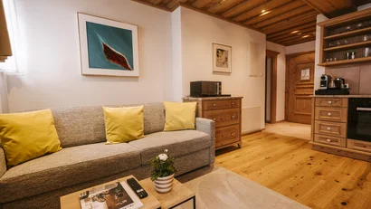 Cozy living room with yellow pillows, wooden furniture, and modern kitchenette