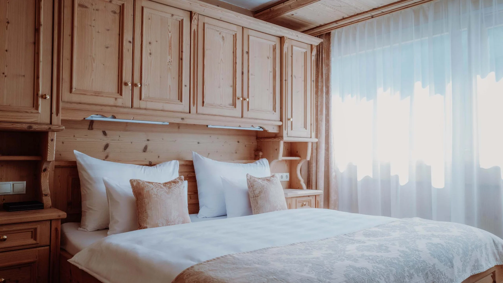 Gemütliches Schlafzimmer mit Holzmöbeln und großem Fenster mit Vorhängen