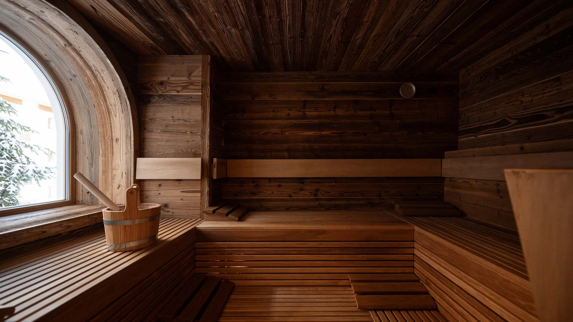 Holzsauna mit großen Fenstern und Saunaeimer mit Schöpfkelle