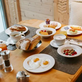 Breakfast table with eggs, bread, fruit, coffee and juices in cozy room