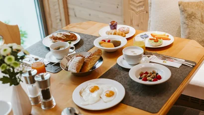 Breakfast table with eggs, bread, fruit, coffee and juices in cozy room