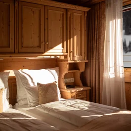 Gemütliches Schlafzimmer mit Holzverkleidung und Blick auf verschneite Berge