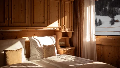 Gemütliches Schlafzimmer mit Holzverkleidung und Blick auf verschneite Berge