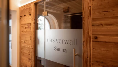 Eingang zu einer Sauna mit Holzrahmen und beschrifteter Glastür
