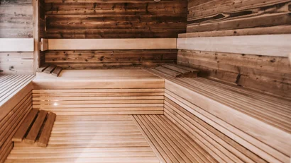 Empty sauna room with wooden benches and wall clock