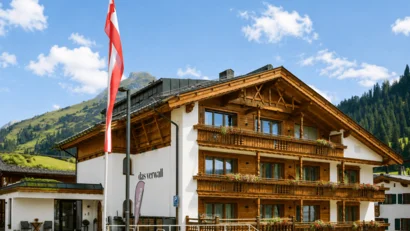 Wooden house with balconies and Austrian flag against mountain backdrop