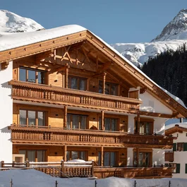 Holz Chalet im Schnee vor verschneiten Bergen und klarem Himmel