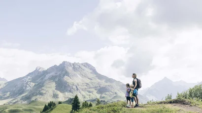 Mutter mit zwei Kindern wandert in den Bergen bei bewölktem Himmel
