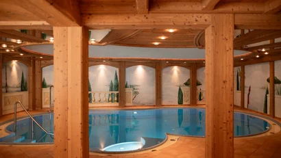 Runder Innenpool mit Holzsäulen und Wandmalereien in warmem Licht